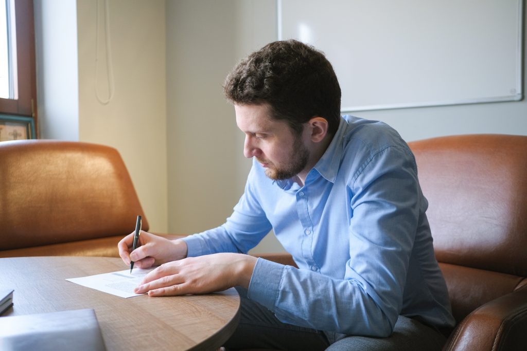 Man writing on a piece of paper while sitting at his desk