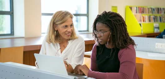 Two women working together in the school library