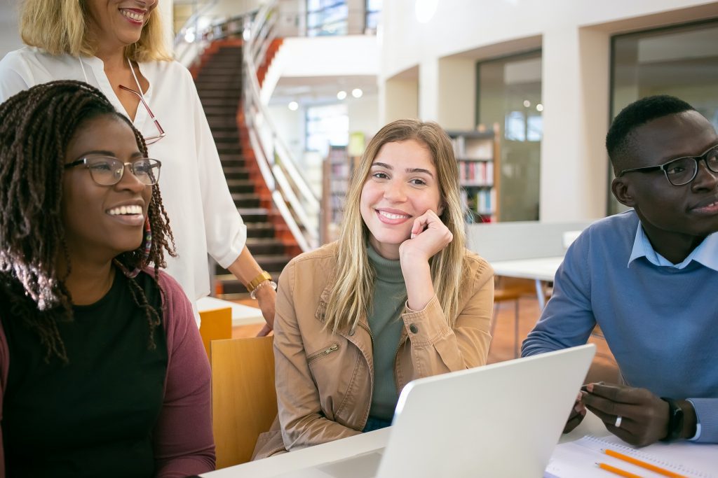 woman smiling in center of picture with colleagues sitting around her