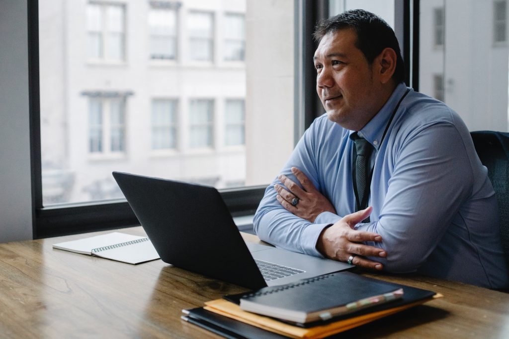 Man sitting at office desk with laptop open in front of him