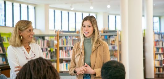 Two women talking in front of a class in the library