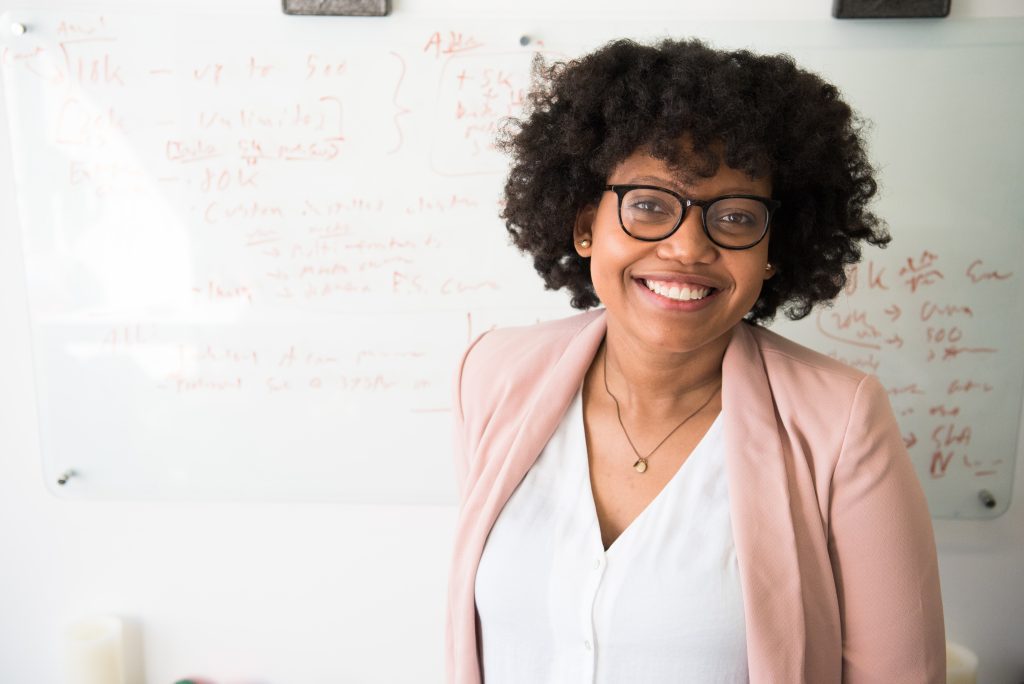 Woman standing in front of whiteboard smiling