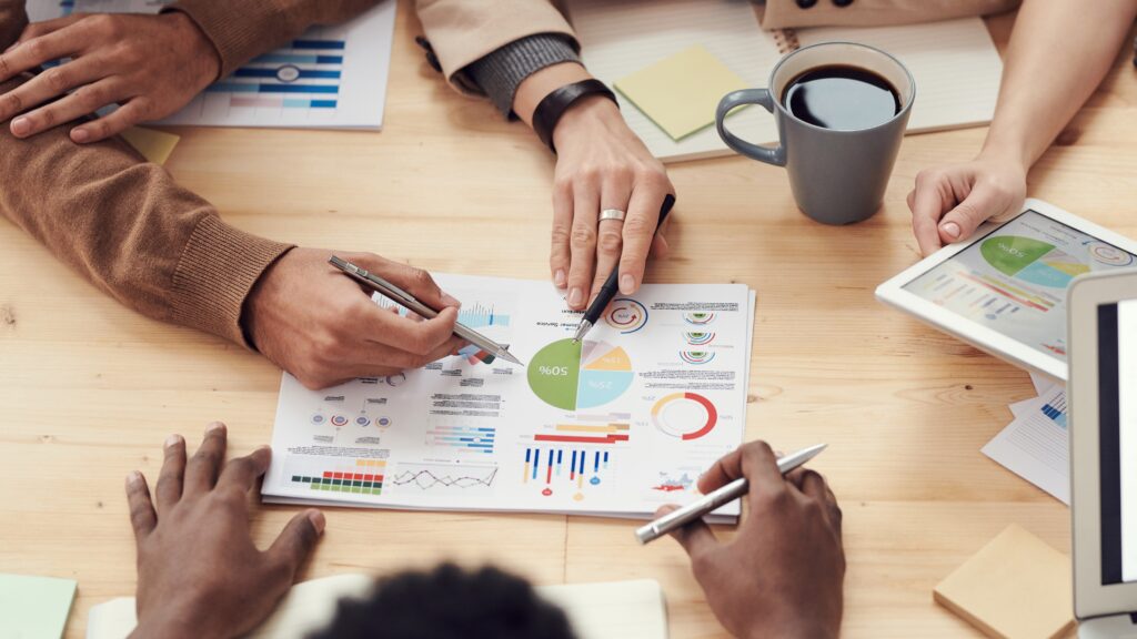People gathered around a table looking at graphs and  charts