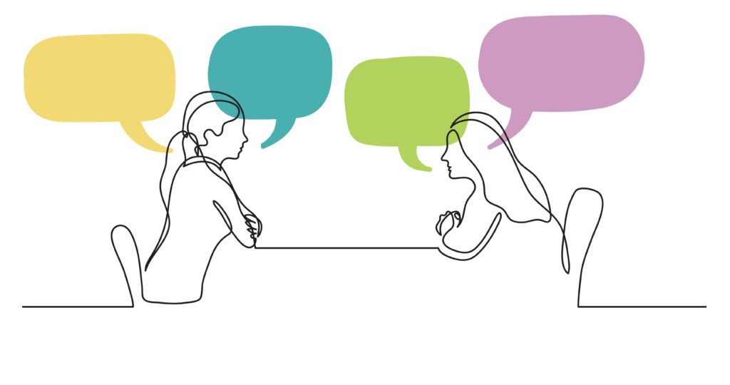 Two women sitting behind a table talking with speech bubbles