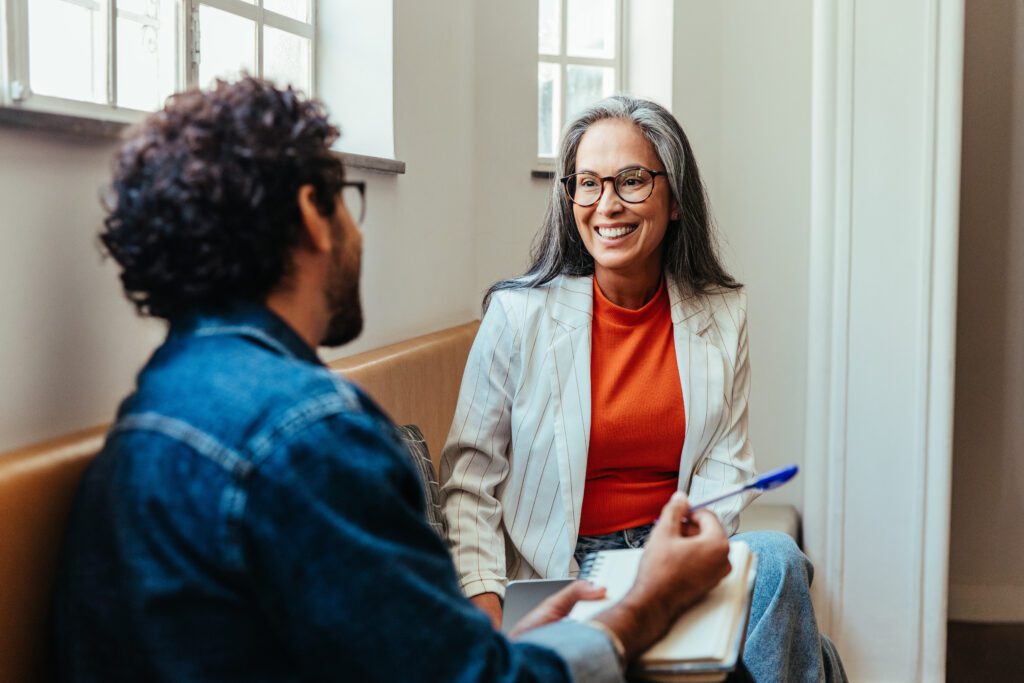 Two coworkers engaging in a conversation while seated in an office lounge area