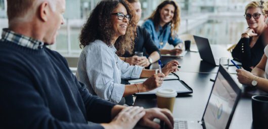 Multi-ethnic business people smiling during a meeting in conference room. Team of professionals having meeting in boardroom.