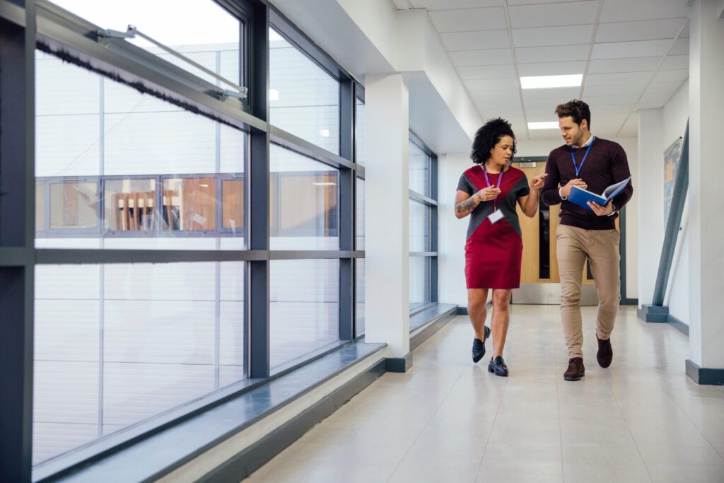 Two teachers are having a conversation while walking together in a school hallway